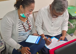
With the assistance of a peer monitor, a client in Indonesia fills out a survey with the help of an app-equipped tablet. (Photo courtesy Yayasan Peduli Hati Bangsa)