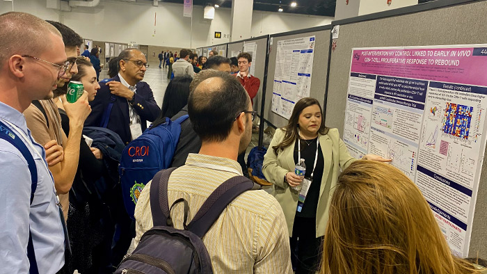 Demi Sandel, a fourth-year PhD student in the UCSF Biomedical Sciences program, presenting her poster to a crowd of intent listeners.