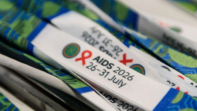 Event badges for amfAR at AIDS 2026 conference with red ribbon logo.