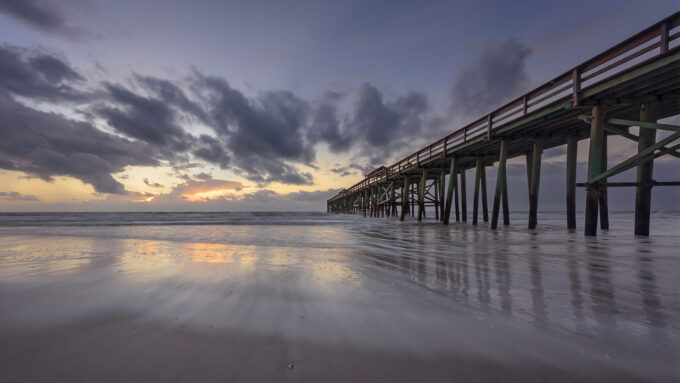Scenic view of a pier extending into the ocean at sunset.