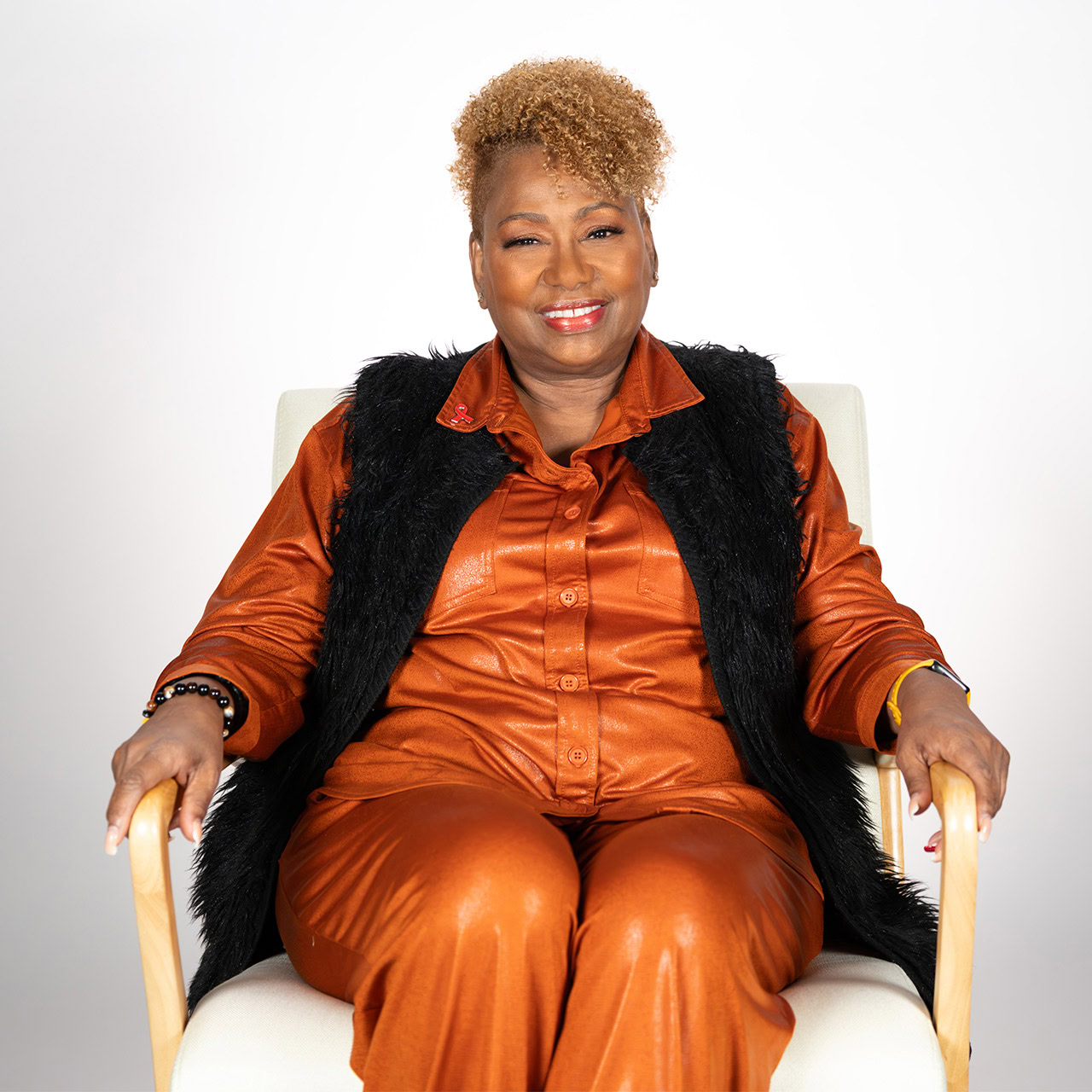 Smiling woman in orange outfit supporting amfAR for HIV/AIDS awareness.