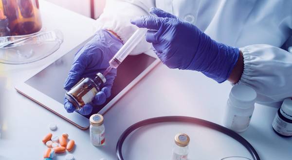 Gloved hands filling a syringe from a medicine vial.
