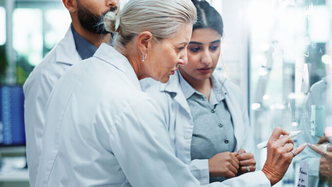 AmfAR research team analyzing data on a glass board in a lab.